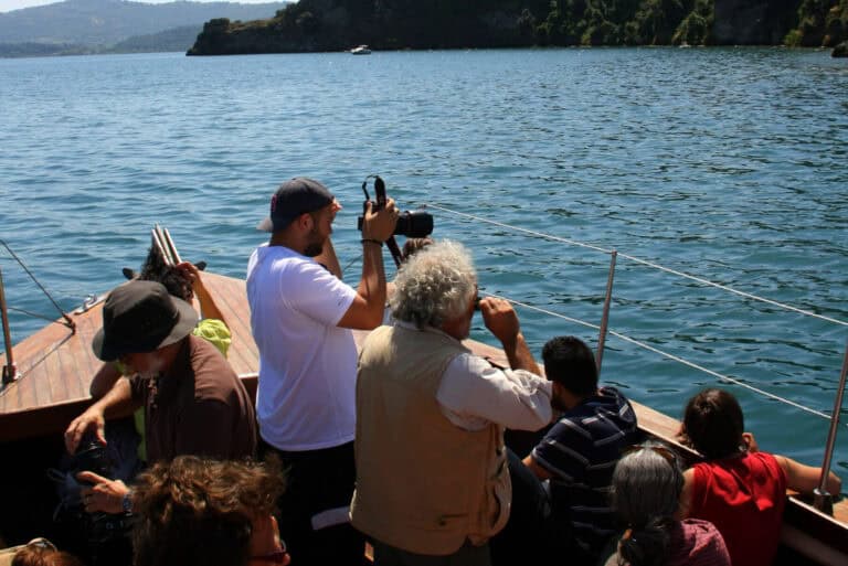 Tourists enjoying a boat ride on Lake Bolsena while taking photos.