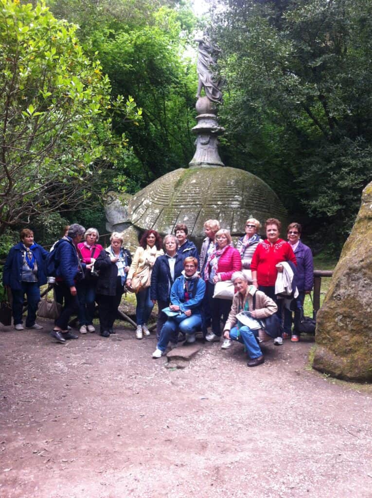 Group of visitors at the Parco dei Mostri in Bomarzo, Italy, near a turtle sculpture.