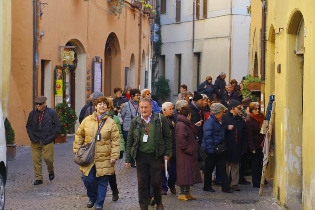 Group of people walking and chatting in a city street, some smiling.